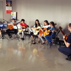 guitar students playing with their guitar teacher